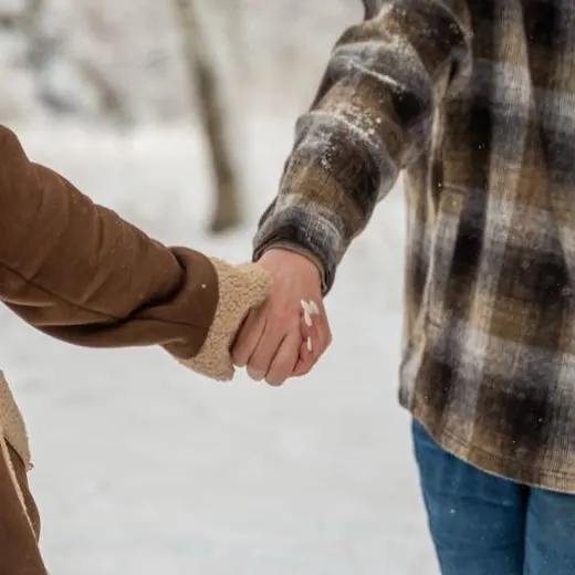Close-up of the couple holding hands in the snow