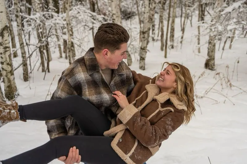Couple laughing as he lifts her in the snow